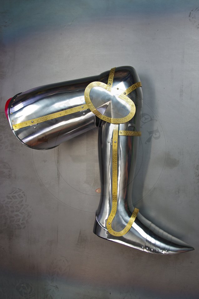 English style leg harness with fully closed cuisses, full greaves with characteristic line around outside ankles. Demi-greaves connected with greaves on rotary pin. Made of medium carbon steel of various thickness from 1 mm up to 1,5 mm. Heat hardened and tempered up to 42 HRC. Brass bands decoration motive based on example visible on Henry V tournament helm. Hand made steel buckles in set./Osony ng w stylu angielskim z w peni zamknitymi nabiodrkami, nagolennicami z charakterystyczn lini wok zewntrznej kostki. Demi-greave poczony z nagolennicami poprzez obrotowy pin. Wykonane ze stali redniowglowej rnej gruboci od 1 mm do 1,5 mm. Hartowane i odpuszczane do 42 HRC. Mosine listwy dekoracyjne z motywem wzorowanym na hemie turniejowym Henryka V. W zestawie rcznie robione sprzczki stalowe.